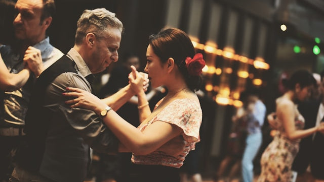Two people dancing in a social setting with blurred background